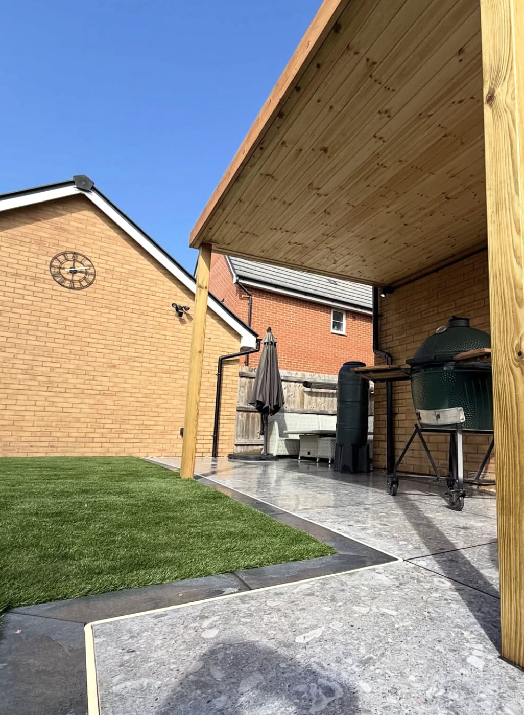 Timber canopy over an outdoor kitchen area beside artificial grass