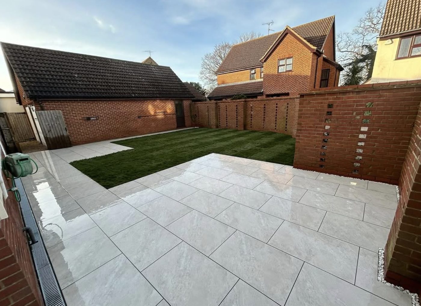Large light porcelain patio with a new lawn and brick garden walls
