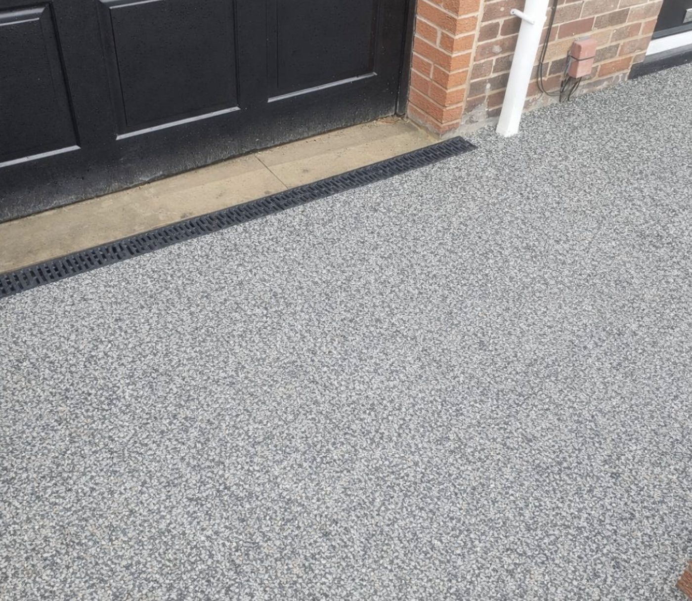 Resin bound driveway with a black channel drain across a doorway threshold